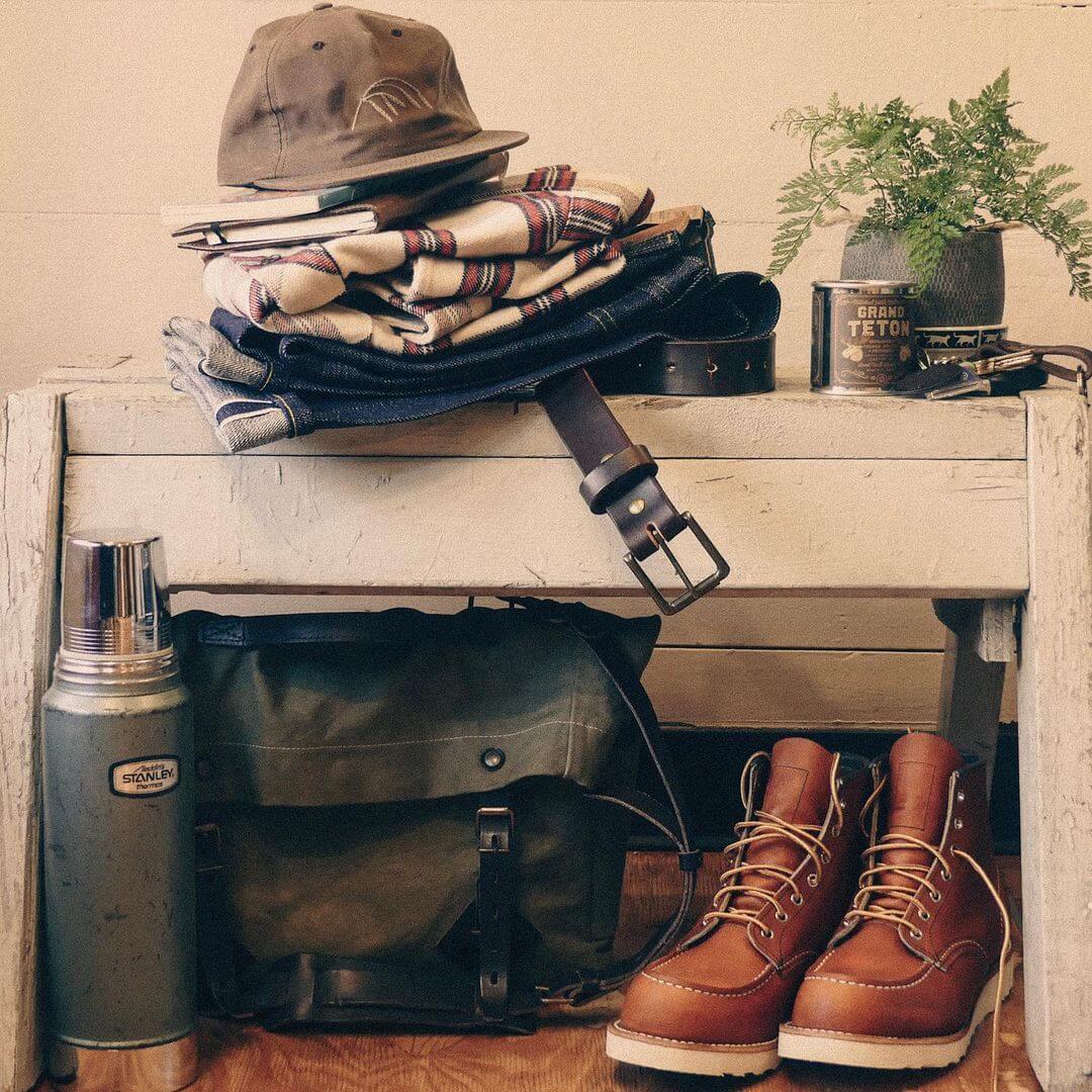 Shirt, pants, hat, bag, and thermos displayed on a bench