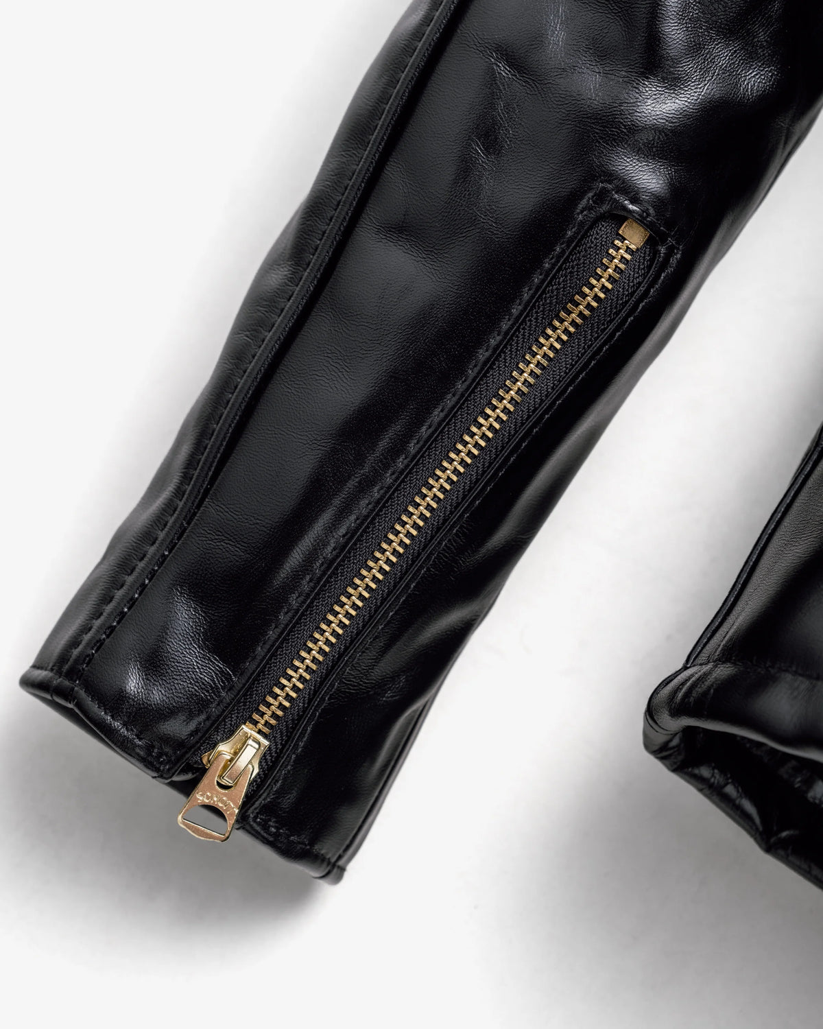 Detail shot of polished brass sleeve zipper with Schott branding. See product details for more information.