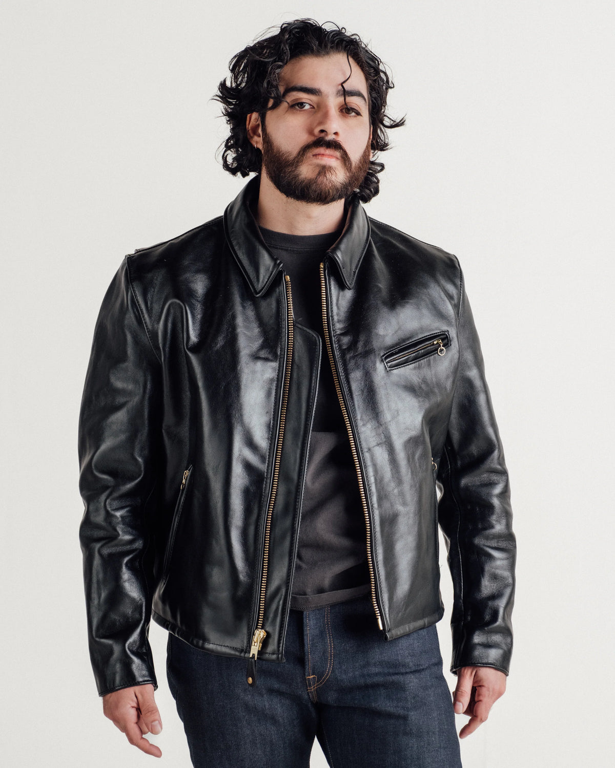 Male model wearing black horsehide leather jacket with denim jeans. See product details for more information.