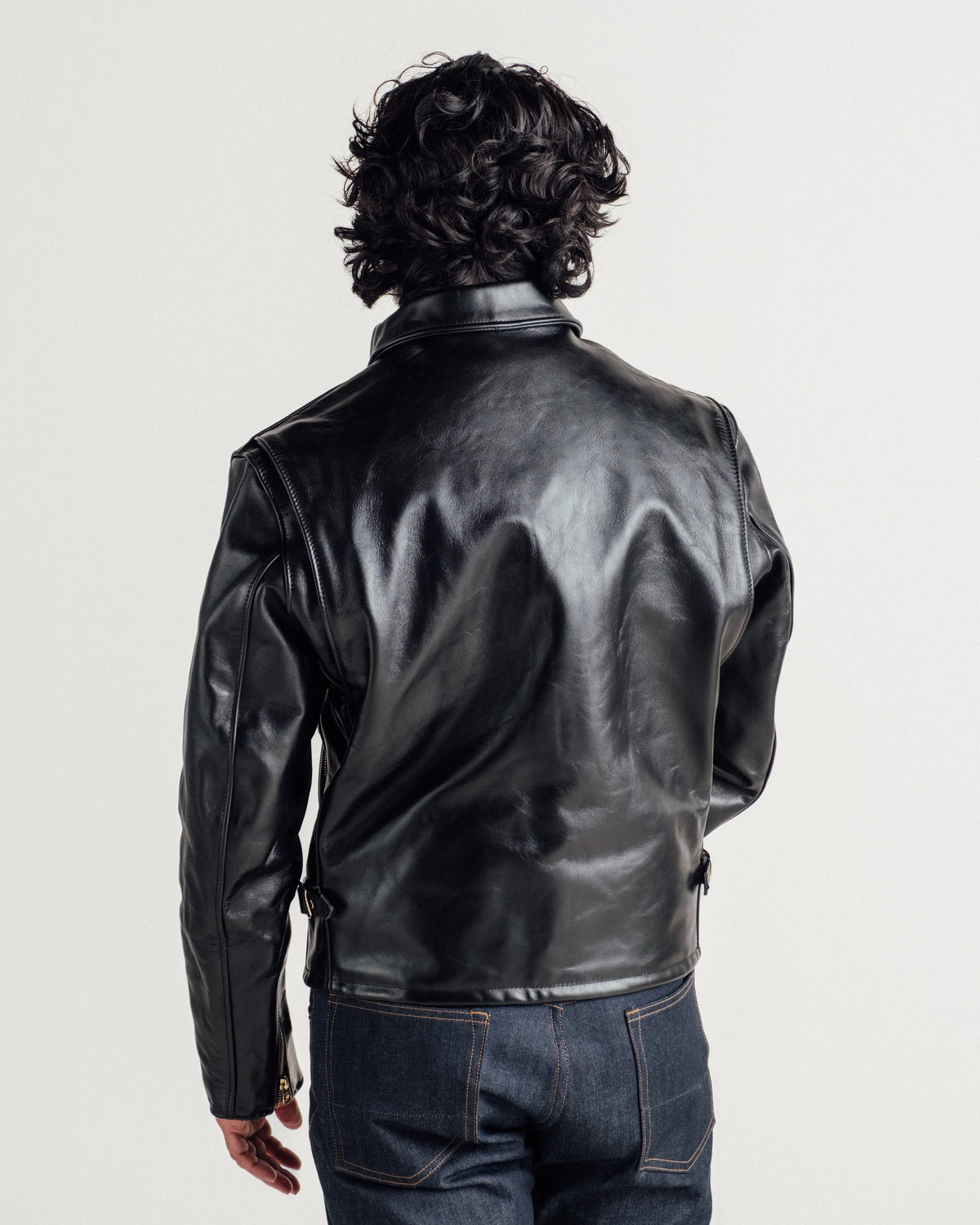 Rear shot of man wearing black horsehide leather jacket with denim. See product details for more information.
