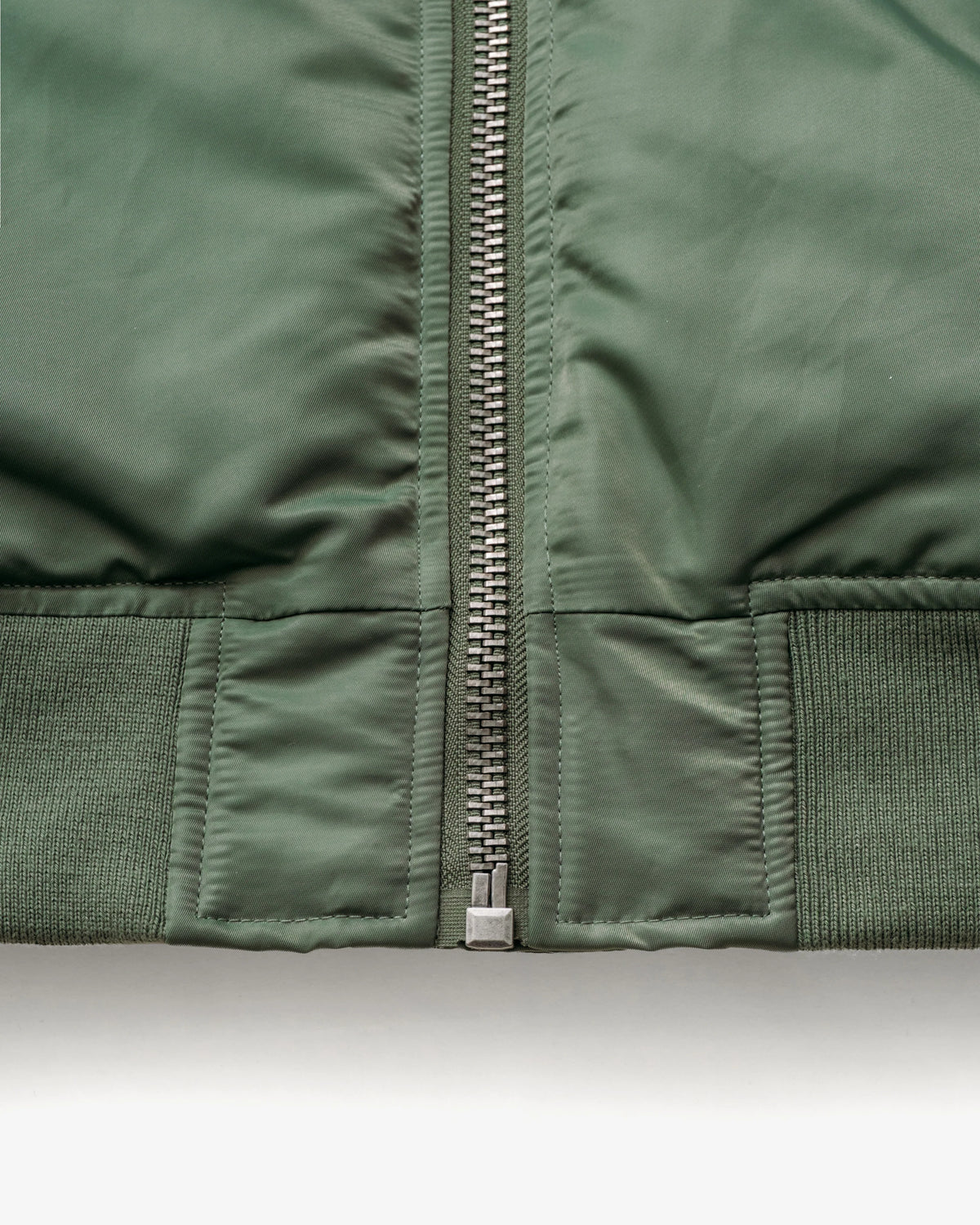 Waist rib knit detail shot of sage bomber jacket. See product details for more information.