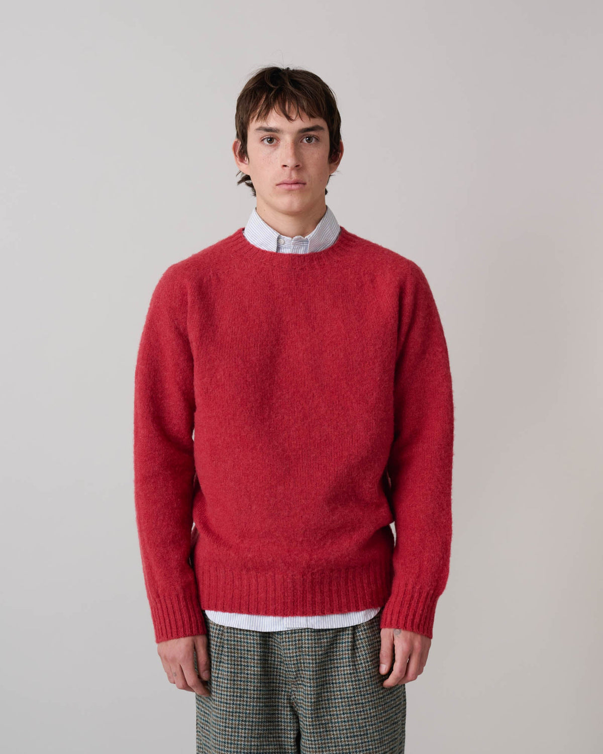 Guy wearing Birth of the Cool sweater in Velvet Kiss (red) over a blue stripe oxford button down and checked pants. See product description for more details.