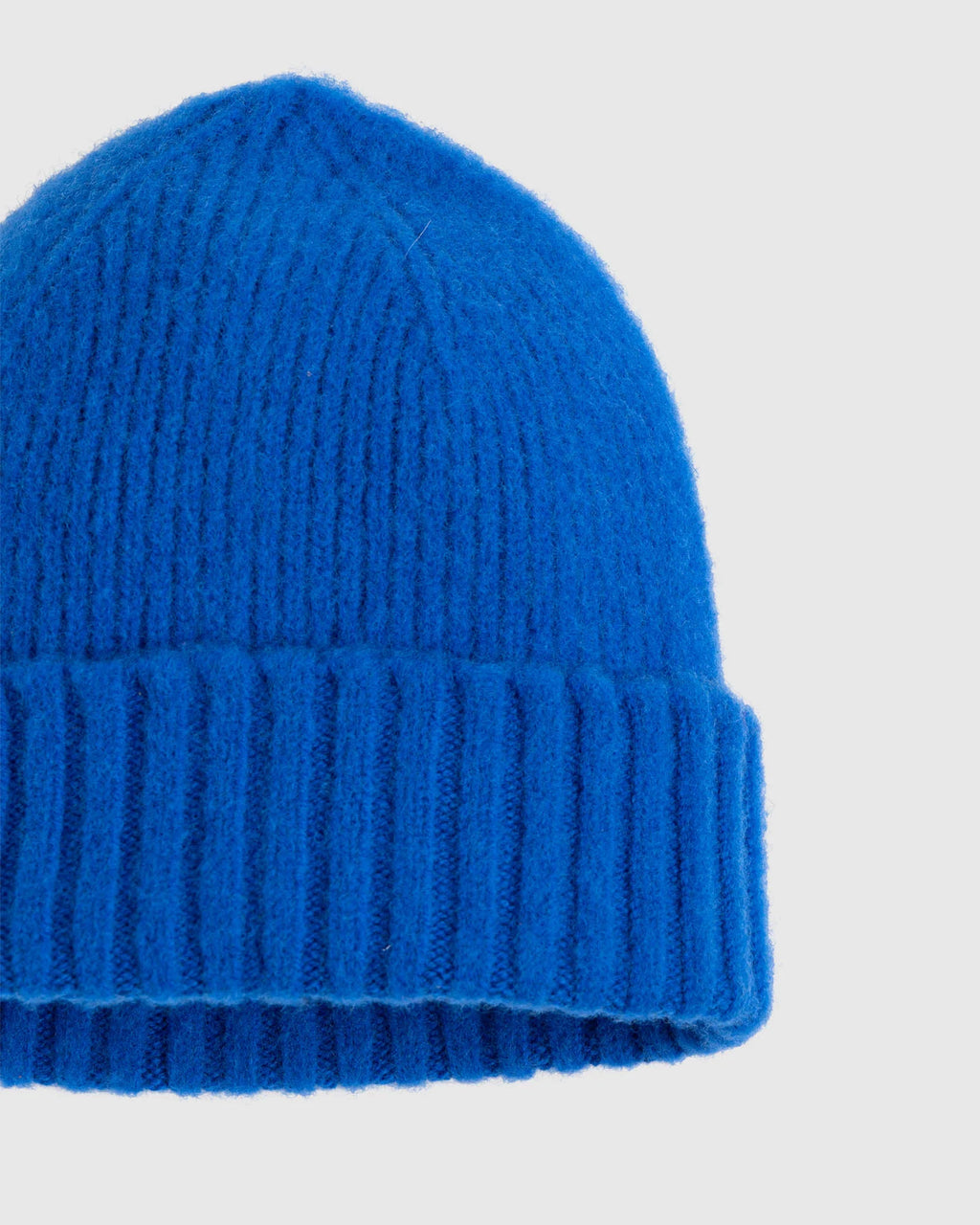 Slightly closer shot of flat lay of classic wool beanie, blue color, showing some wool texture. See product details for more information.