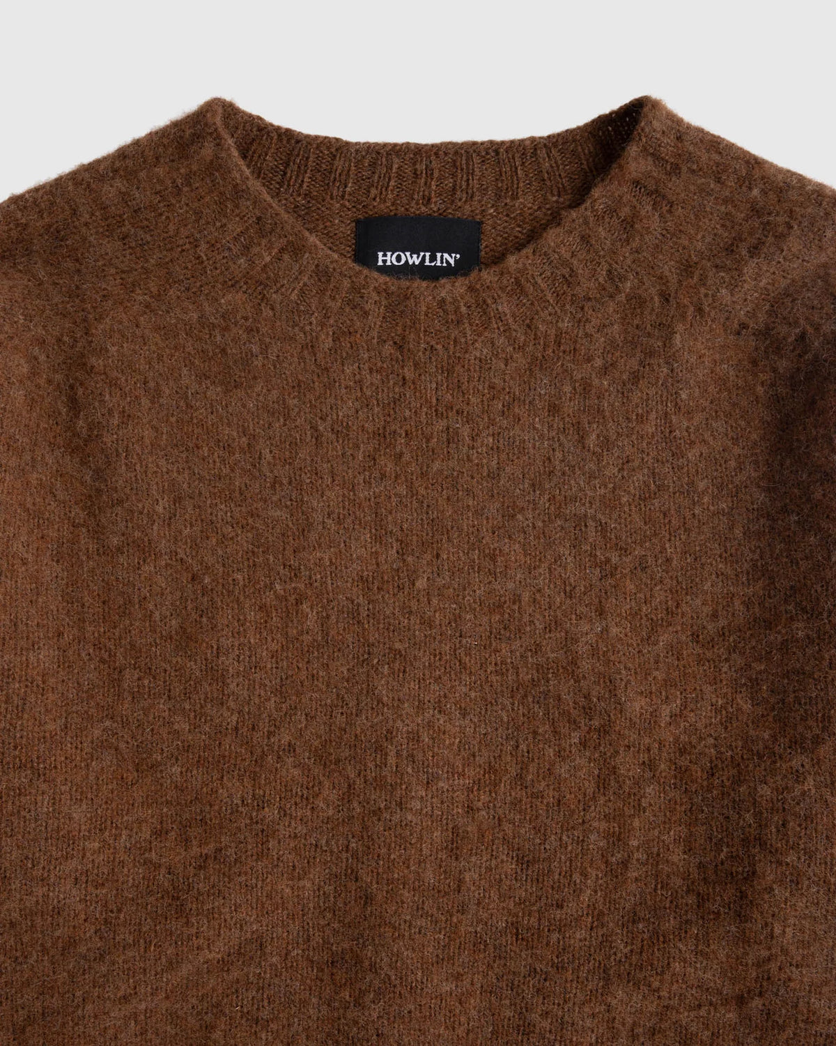 Flat lay of brown shetland wool sweater, zoomed on collar. Howlin' label visible. See product description for more details.